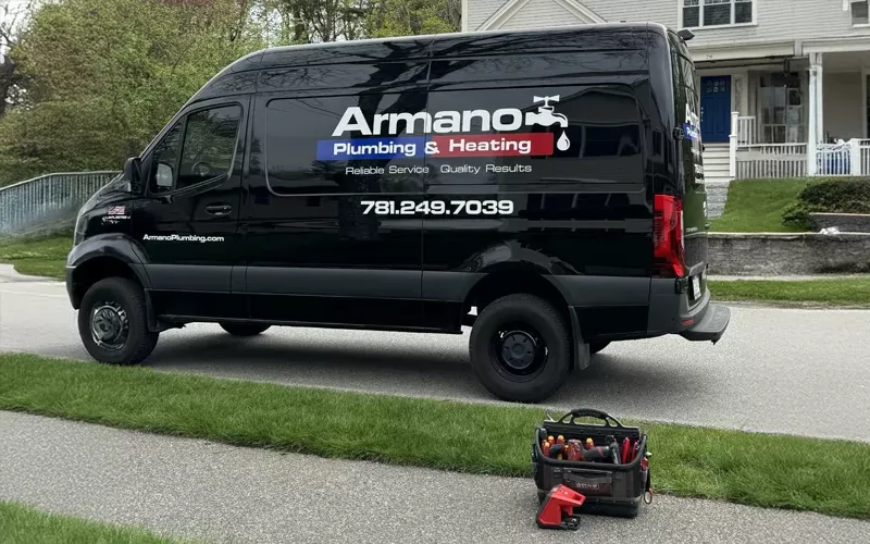 Armano Plumbing & Heating service van parked on a residential street, with a tool bag placed on the grass nearby.